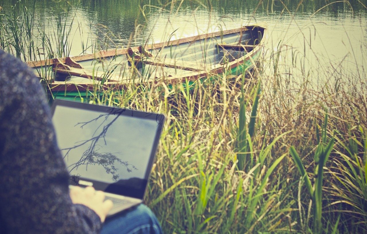 Man with laptop by the river